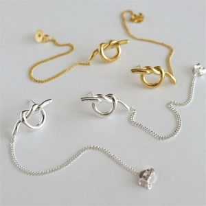 Detail of minimalist 925 sterling silver knotted long chain drop earrings in gold and silver