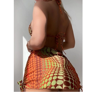 Three-piece bikini set with orange gradient halter top and polka dot skirt back view