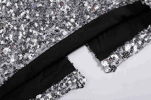 Gros plan des paillettes argentées et de la doublure noire sur la robe de soirée