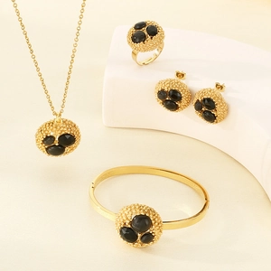 Detailed view of luxury gold jewelry set with black stones on elegant beige display