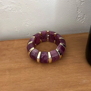 Détail de résine marbrée violette et de blocs en métal doré sur un bracelet élastique