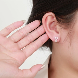 Elegant silver heart earrings with pearls and crystals shown on model's ear