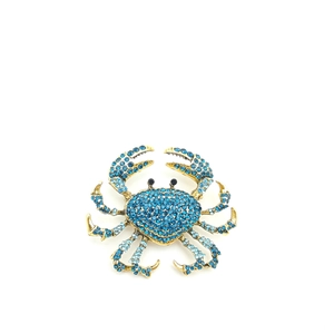 Detailed close-up of a golden crab brooch with sparkling blue rhinestones and black eyes