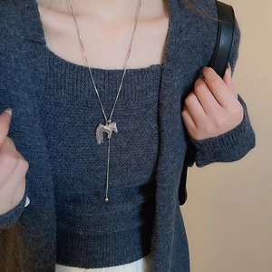 Close-up of a silver brushed hollow horse pendant necklace on model with snake chain