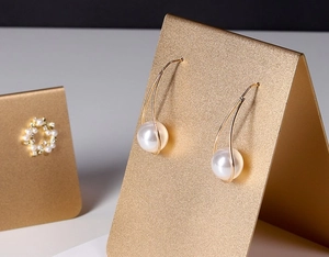 Detail of elegant pearl drop earrings with double gold metal hooks on display stand