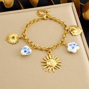 Detailed view of gold chain bracelet with sun pendants and blue floral ceramic heart beads
