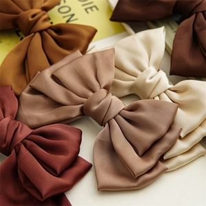 Detailed view of large multi-layered satin bow hair clips in earthy silk tones