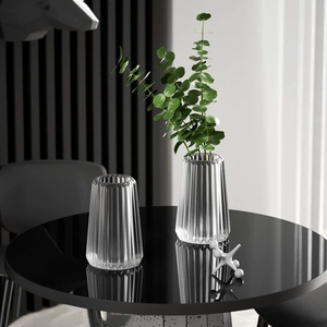 Modern vertical stripe glass vases on reflective black table with green eucalyptus