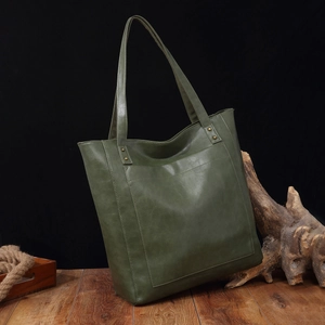 Détail d'un sac cabas vintage en cuir vert foncé avec grande poche et rivets métalliques