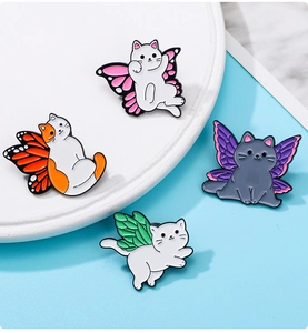 Détail de quatre épingles en émail de chats avec des ailes de papillon colorées