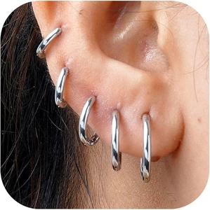 Close-up of five minimalist silver hoop earrings worn along the ear lobe and cartilage