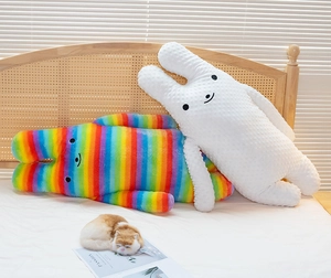 Detail of white 3D bubble fleece and rainbow striped long rabbit plush pillows in bed