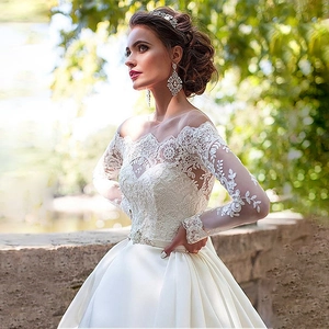 Elegant off-shoulder white lace and satin bridal gown with long sleeves and cathedral train