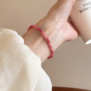 Lifestyle-Ansicht eines rosa Kristallperlenarmbands am Handgelenk mit Kaffeetasse
