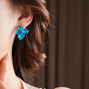Macro view of bright blue cube crystal flower cluster stud earrings on a model