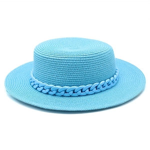 Detail of light blue woven boater hat featuring a stylish matte plastic chain decoration