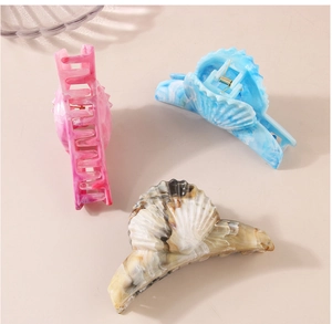 Macro detail of three shell-shaped marble hair claws in pink, blue and amber