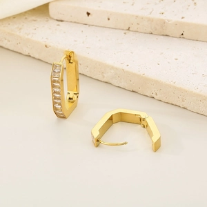 Macro shot of gold geometric earrings with rectangular cubic zirconia on stone base