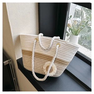 Close-up of woven straw tote bag with white daisy flower detail and cotton rope handles