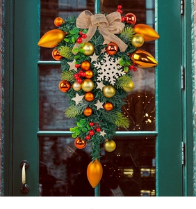 Close-up of Christmas teardrop swag with pine branches, red berries and burlap bow on door