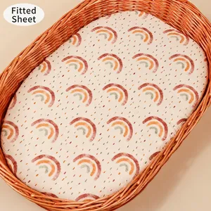 Detail of soft cotton baby bassinet sheet with vintage rainbow print on a basket mattress