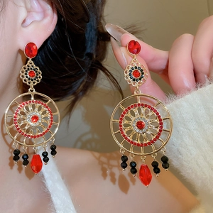 Détail de boucles d'oreilles vintage avec pendentif goutte rouge et finitions dorées chic
