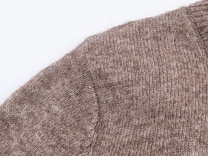 Close-up of brown and white blended knit fabric showing wool texture and seam detail