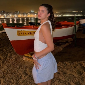 White halter backless top paired with blue striped shorts on a night beach setting