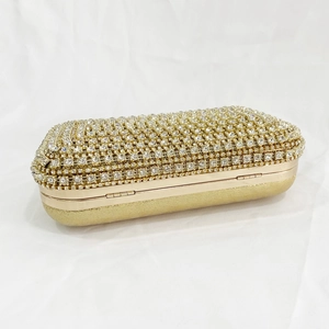 Macro shot of luxury gold evening clutch with sparkling rhinestones and matte metal finish
