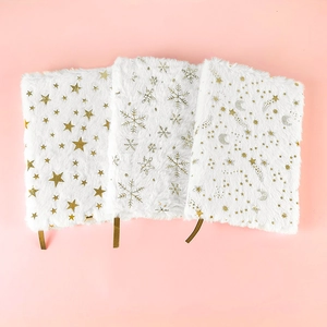 Detail of plush white notebooks with gold stamped stars, snowflakes and ribbon bookmarks
