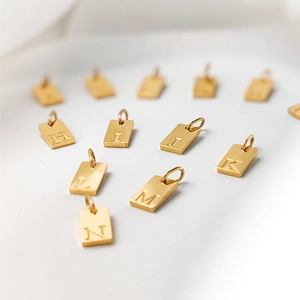 Macro shot of gold square alphabet charms with engraved letters H, I, J, K, L, M, and N