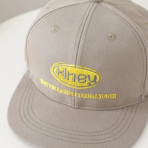 Kids hip hop flat brim cap in light grey featuring yellow oval letter embroidery