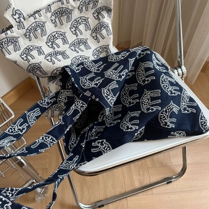 Close-up of embroidered canvas tote bags with abstract animal patterns on a modern chair