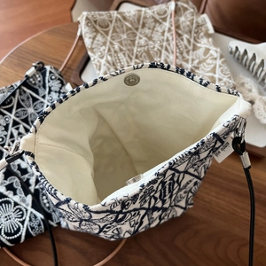 Detail of embroidered canvas crossbody bag set with leather straps and magnetic closure
