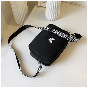 Detail of nylon crossbody bag featuring a silver butterfly logo and wide lettered strap