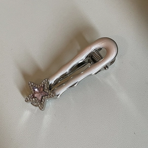 Gros plan sur une pince à cheveux argentée avec une étoile rose scintillante et strass