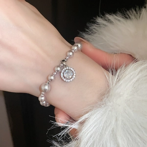 Close-up of pearl bracelet with pavé zircon round pendant on model wearing white fur