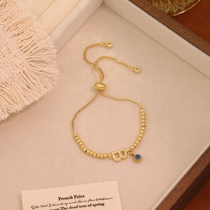 Dettaglio del bracciale a sfere dorate regolabile con occhio greco e ciondolo lettera B