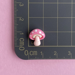 Macro shot of a tiny pink resin mushroom charm on a measuring mat for nail art use