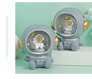 Detail of grey astronaut figurines with golden accents and internal LED fairy lights
