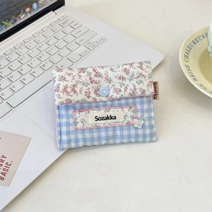 Detailed view of a floral plaid fabric pouch with blue button on a white laptop