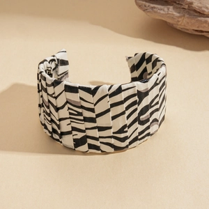 Detailed view of wide open cuff bracelet with black and white zebra print and pleated texture