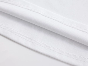 Detailed close-up of white knitted crop top showing precise double-stitch hem and soft fabric