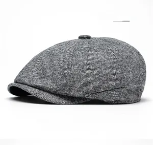 Macro shot of light gray tweed texture and top button on a winter newsboy cap