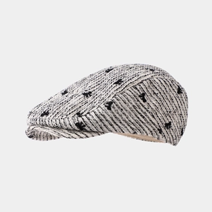 Detail of tweed newsboy cap with black floral jacquard pattern and textured knit