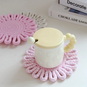 Close-up of handmade flower-shaped woven cotton trivet in pink and white striped pattern