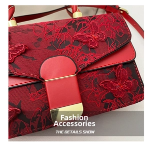 Detail shot of a red handbag featuring floral embroidery and a gold rectangle lock