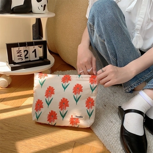 Detailed side view of a floral cotton makeup bag with Sozakka label in soft natural light