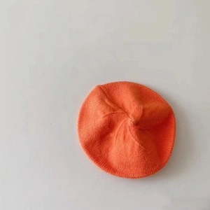 Detail of soft orange knitted wool beret fabric texture and vibrant candy color