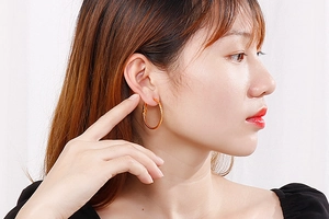 Golden large hoop earrings shown on model with polished geometric metallic finish